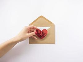 uma mulher tem um coração vermelho na mão pronto para enviá-lo como um cartão postal para o dia dos namorados foto