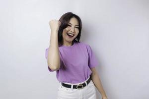 uma jovem mulher asiática com uma expressão de sucesso feliz vestindo camisa roxa lilás isolada por fundo branco foto