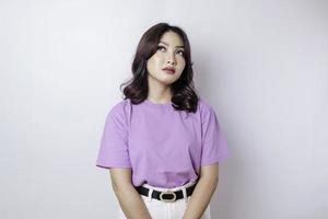 um retrato de uma mulher asiática vestindo uma camiseta roxa lilás isolada por fundo branco parece deprimido foto