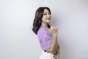 sorrindo linda mulher asiática apontando o dedo para o espaço vazio ao lado de seu fundo branco isolado foto