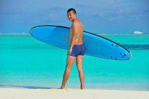 homem com prancha de surf na praia foto