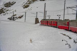 trem vermelho na neve nos Alpes suíços foto