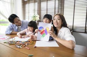 família asiática com crianças desenhando e pintando na mesa na sala de jogos em casa, jogo educativo. foto