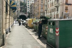 genoa, itália - 9 de junho de 2017 - migrante procurando comida dentro do recipiente de lixo foto