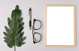 quadro branco, caneta, óculos e galhos de folhas em fundo branco foto