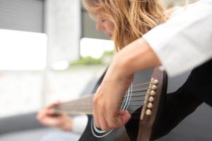 mulher toca seu violão canhoto em casa depois do trabalho no escritório foto