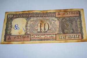 rara nota de moeda indiana de dez rúpias em fundo branco, governo da índia nota de dez rúpias antiga moeda indiana, velha nota de moeda indiana em cima da mesa foto