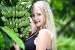 uma linda mulher vestindo roupas de ginástica em pé por bananeira e curtindo a natureza no jardim durante o dia. foto