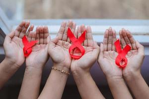 muitas mãos segurando fitas vermelhas para aids ou fundo de campanha de câncer