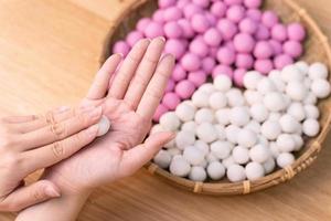 uma mulher asiática está fazendo tang yuan, yuan xiao, bolinhos de arroz de comida tradicional chinesa em vermelho e branco para o ano novo lunar, festival de inverno, close-up. foto