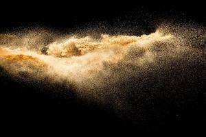 explosão de areia seca do rio. respingos de areia de cor dourada contra um fundo preto. foto