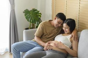 jovem grávida com marido abraçando e esperando um bebê em casa foto