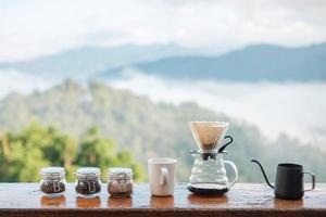 café arábica por equipamento de gotejamento de café vintage definido na mesa de madeira pela manhã com fundo de montanha e natureza foto