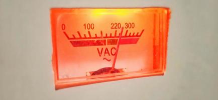 um display de equipamento elétrico antigo medidor de volt ampere vermelho-alaranjado isolado sob condições de pouca luz. foto