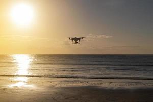silhueta de drone profissional voando perto da praia em uma tarde de verão foto