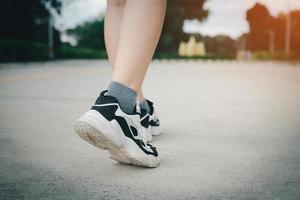 close-up de sapatos de mulher jovem caminhando ao ar livre em tênis de corrida por trás. foto