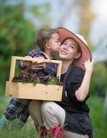 uma linda mãe passa tempo com seu filho no jardim. eles estão coletando legumes em cestas. foto