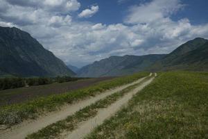 fita da estrada entre as encostas das montanhas nas extensões de altai em um dia de verão foto