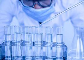 um cientista do sexo masculino usando óculos de proteção e luvas está pingando produtos químicos para testar uma vacina. bioquímicos estão realizando experimentos para descobrir novas drogas. pesquisadores trabalham em laboratórios de ciências.