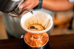café por gotejamento, barista derramando água no café moído com filtro foto