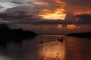 pescador em seu barco ao pôr do sol. barco de pescadores ao pôr do sol foto