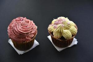 bolos doces com creme e granulado em um fundo preto. deliciosas tortas no café da manhã no preto. foto