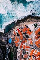 vista aérea das azenhas do mar de cima, vista do telhado vermelho de uma pequena cidade ao longo da costa portuguesa de frente para o oceano atlântico, colares, portugal. foto