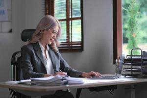 encantadora empresária trabalhando no laptop em seu local de trabalho no escritório moderno. foto