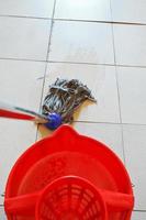 limpeza do piso de ladrilhos por cotonete e balde vermelho foto