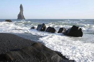 ondas chegando na praia negra de reynisfjara, islândia, com formações rochosas ao fundo foto