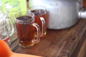dois copos de chá doce em uma mesa de madeira foto