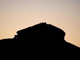 silhueta de pessoas ao pôr do sol na rocha foto