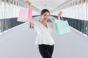 retrato de mulher sorridente feliz com sacolas de compras no corredor a pé. mulher bonita com um saco de papel. foto