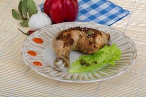 perna de frango assado no prato e fundo de madeira foto