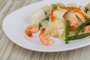 salada de camarão no prato e fundo de madeira foto