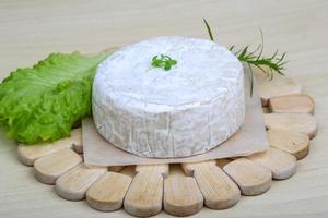 queijo camembert na placa de madeira e fundo branco foto