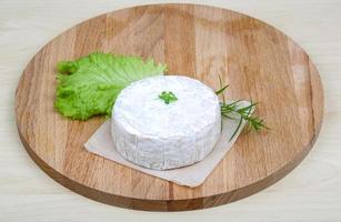 queijo brie na tábua de madeira e fundo de madeira foto