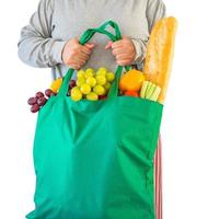 mulher segura sacola de compras reutilizável verde ecologicamente correta cheia de produtos de mercearia frescos completos de frutas e legumes isolados no fundo branco com traçado de recorte foto