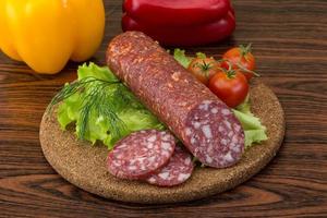 salame na placa de madeira e fundo de madeira foto