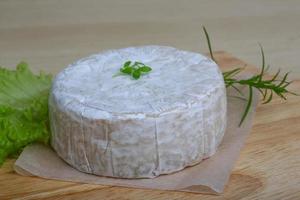 queijo camembert na tábua de madeira e fundo de madeira foto