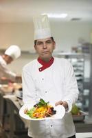 chef na cozinha do hotel preparando e decorando comida foto