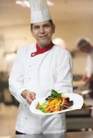 chef na cozinha do hotel preparando e decorando comida foto