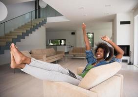 mulher afro-americana em casa na cadeira com telefones tablet e cabeça foto