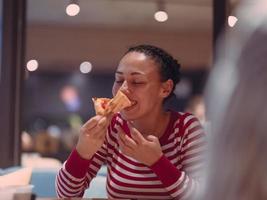 jovem come uma pizza do serviço de entrega no escritório foto