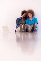 casal multiétnico sentado no chão com um laptop e tablet foto