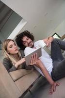 casal relaxando em casa com computadores tablet foto