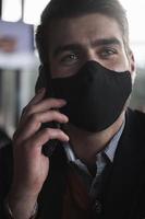 homem de negócios usando máscara facial médica de coronavírus enquanto estiver usando smartphone foto
