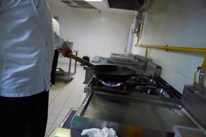 chef na cozinha do hotel preparar comida com fogo foto