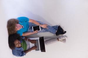 casal multiétnico sentado no chão com um laptop e tablet vista superior foto