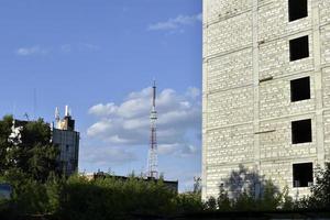 uma antena de telecomunicações na cidade e uma roda gigante com uma casa grande e um céu azul. foto